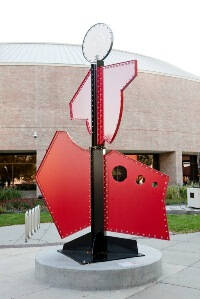 Large red sculpture that looks like a person at the top.